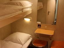 Inside a cabin onboard Skane with bunk beds, a table and a mirror